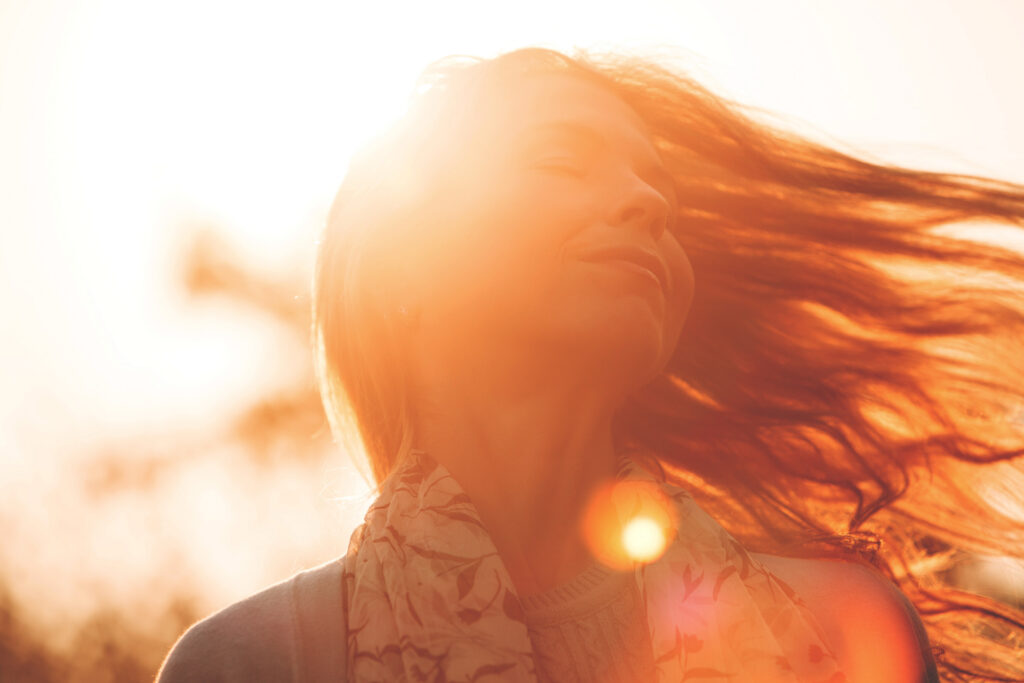 smiling woman in sunburst with flowing hair